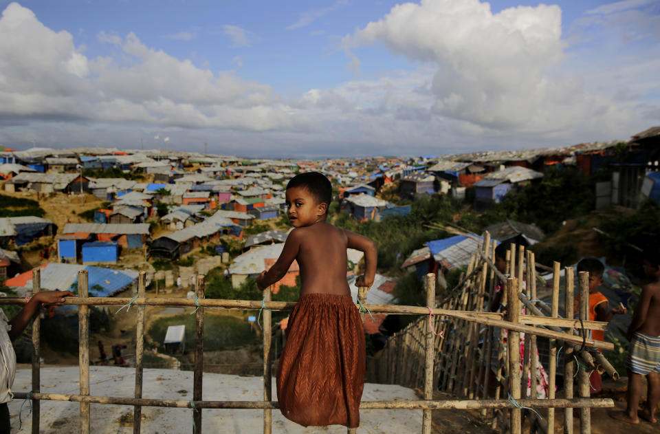 A Rohingya child stands on a bamboo fence overlooking an expanse of makeshift bamboo and tarp shelters at Kutupalong refugee camp, where they have been living amid uncertainty over their future after they fled Myanmar to escape violence a year ago, in Bangladesh, Sunday, Aug. 26, 2018. (AP Photo/Altaf Qadri)