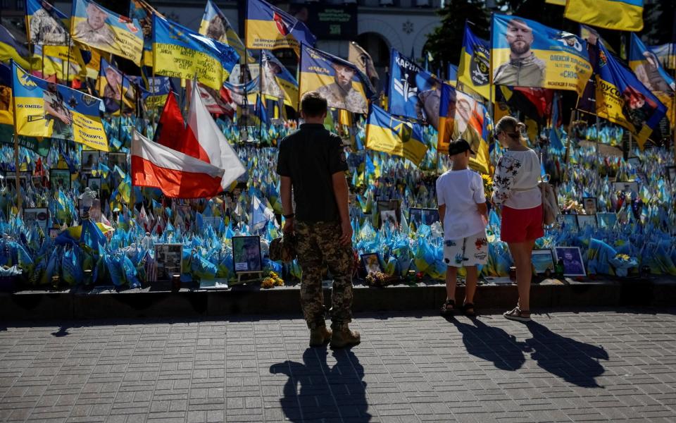 People visit a makeshift memorial with Ukrainian flags, with the names of fallen service members, at the Independence Square