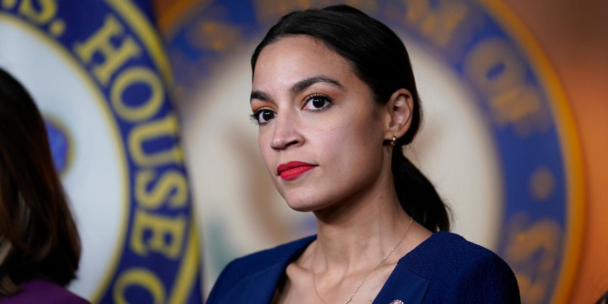 New York Congresswoman Alexandria Ocasio-Cortez in a blue blazer in front of a House of Representatives seal