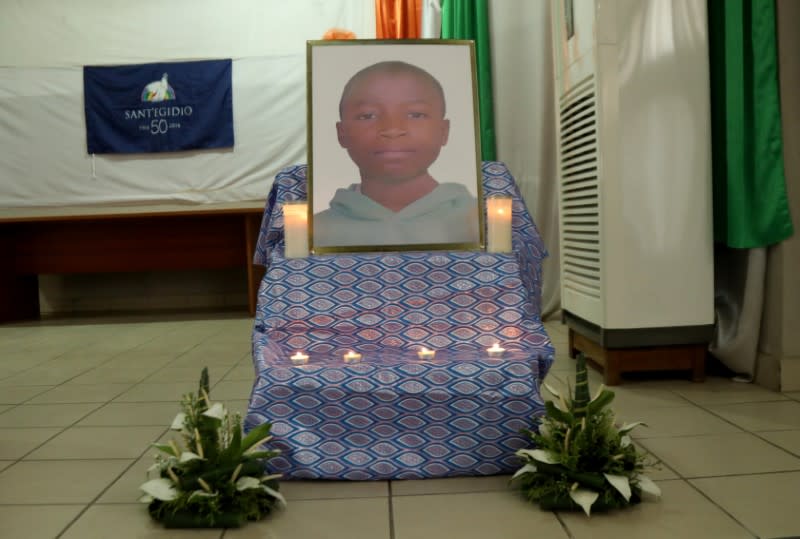 A poster of Barthelemy Laurent Guibahi Ani, a 14 years old boy who was found dead in the undercarriage of an Air France plane, is seen flanked by candles during a tribute prayer in Abidjan