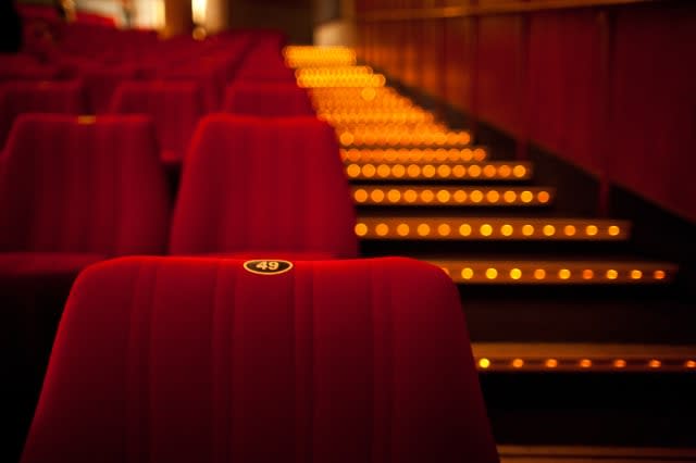 Seat in cinema theater with blurred aisle exit lights.