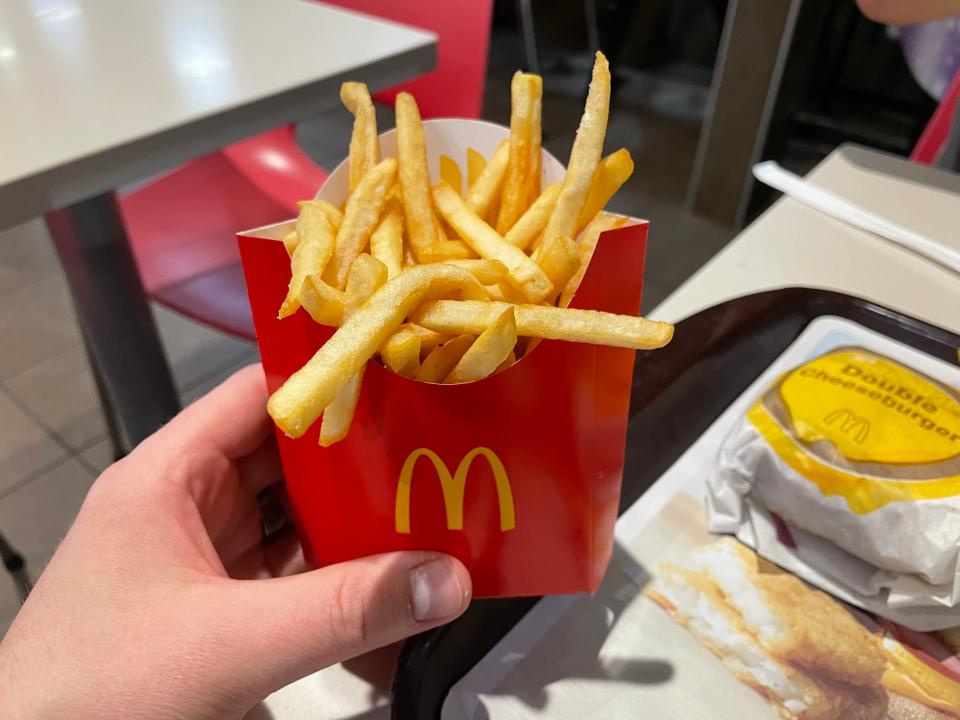 hand holding up a container of mcdonald's french fries