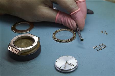 A watchmaker holds the couronne next to other components of an Autore watch model at Buccellati workshop in Chiasso March 14, 2014. REUTERS/Denis Balibouse