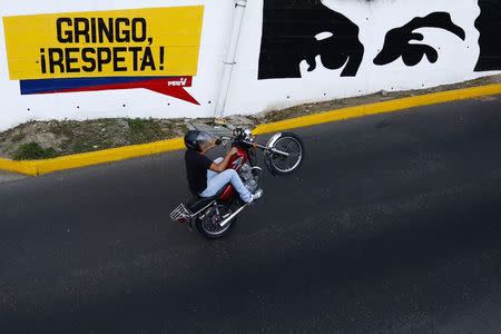 A man rides a motorcycle past a graffiti that reads, "Gringo, respect us!" in Caracas March 9, 2015. The United States on Monday declared Venezuela a national security threat and ordered sanctions against seven officials from the oil-rich country in the worst bilateral diplomatic dispute since socialist President Nicolas Maduro took office in 2013. U.S. REUTERS/Jorge Silva