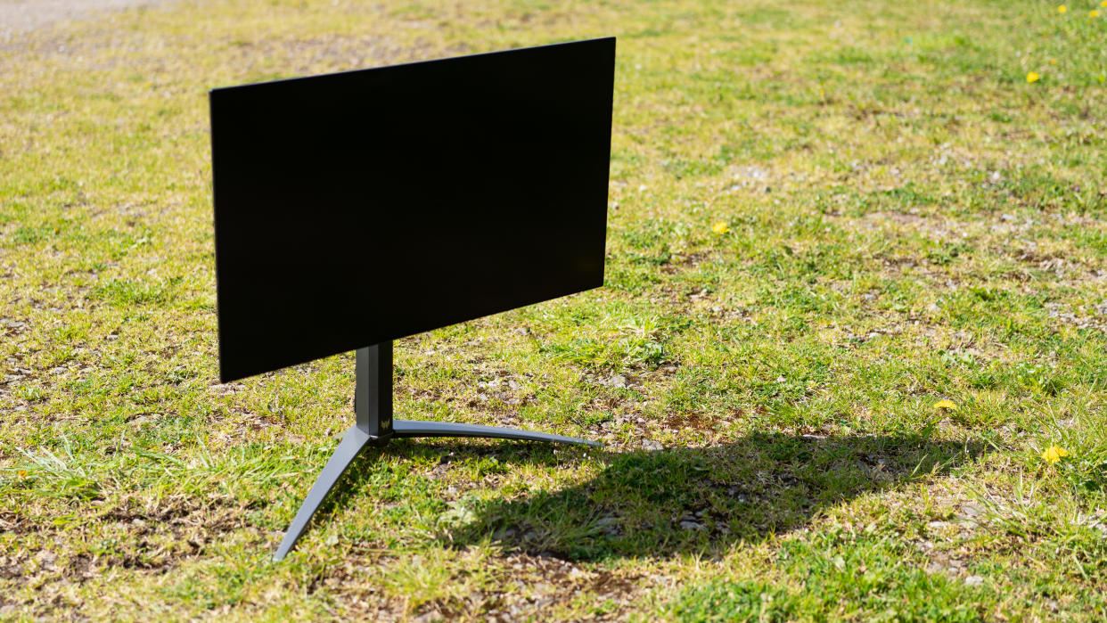  A black Acer Predator X27U monitor sitting on a sunny grass field. 