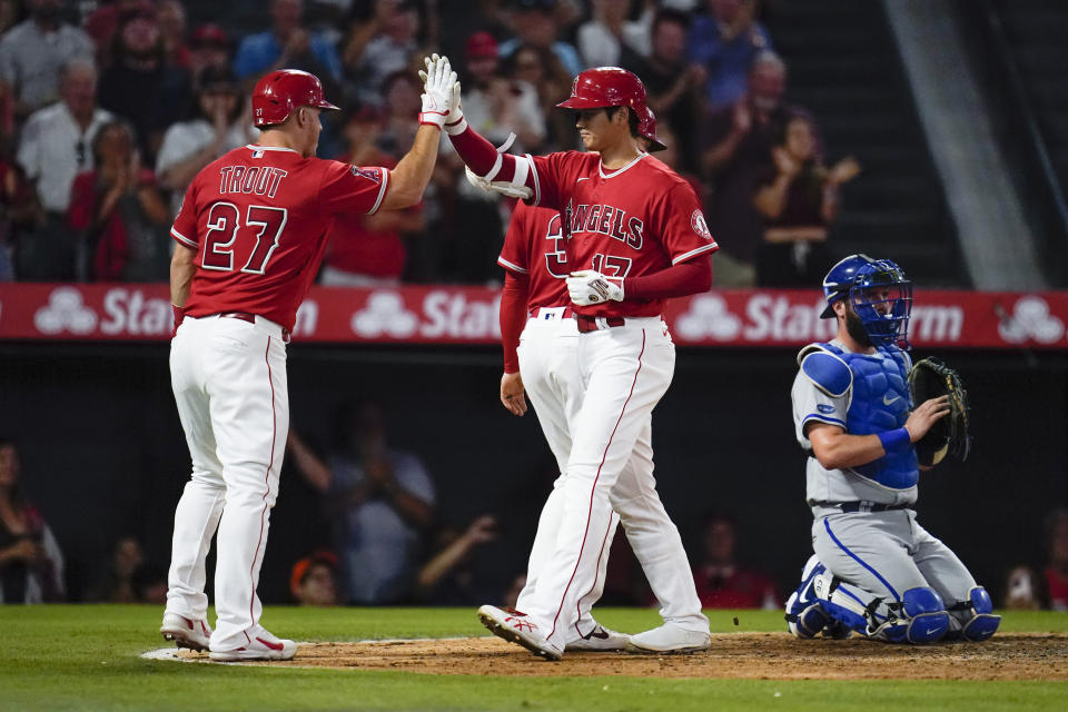 Los Angeles Angels designated hitter Shohei Ohtani (17) high-fives Mike Trout (27) after hitting a home run during the sixth inning of a baseball game against the Kansas City Royals in Anaheim, Calif., Tuesday, June 21, 2022. Taylor Ward (3) and Mike Trout also scored. (AP Photo/Ashley Landis)