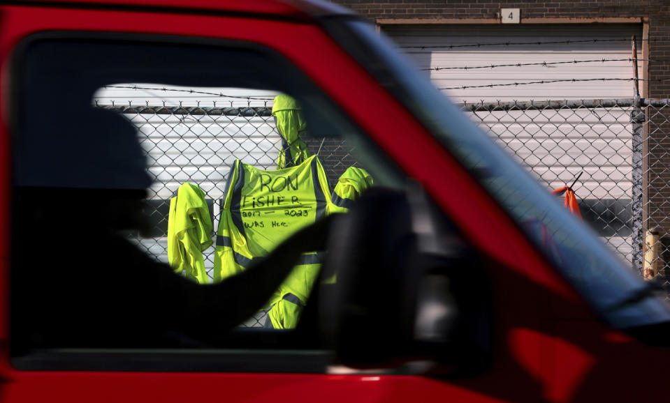 A motorist passes a safety vest for Yellow driver Ron Fisher that was left zip-tied to the fence as the YRC Freight terminal lies shuttered in St. Louis, on Monday, July 31, 2023. Troubled trucking company Yellow Corp. is shutting down and filing for bankruptcy, the Teamsters said Monday. An official backruptcy filing is expected any day for Yellow, after years of financial struggles and growing debt. (Robert Cohen/St. Louis Post-Dispatch via AP)