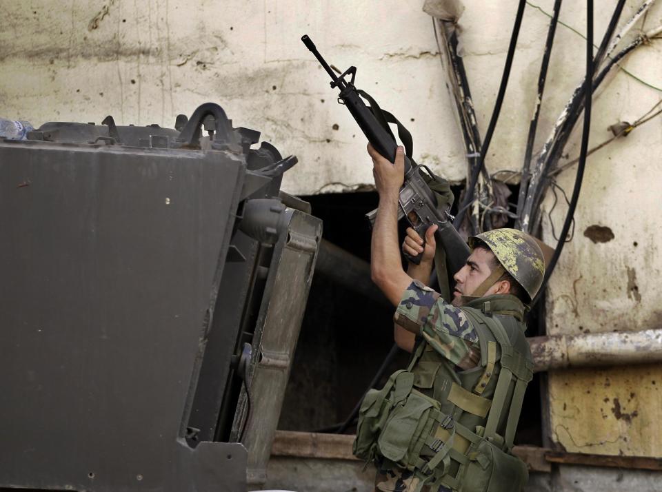 FILE -- In this August 22, 2012, file photo, a Lebanese army soldier fires by his weapon during a clashes between supporters and opponents of the Syrian regime, in the northern port city of Tripoli, Lebanon. From radical preachers to irreverent taxi drivers, anger is spreading through Lebanon’s Sunni community toward the country’s military, adding a dangerous twist to Lebanon’s instability, already shaken by relentless bombings. Many Sunnis accuse the military of siding with their rivals, the powerful Shiite group Hezbollah, as sectarian tensions grow in Lebanon, stoked by the civil war in neighboring Syria. (AP Photo/Hussein Malla, File)