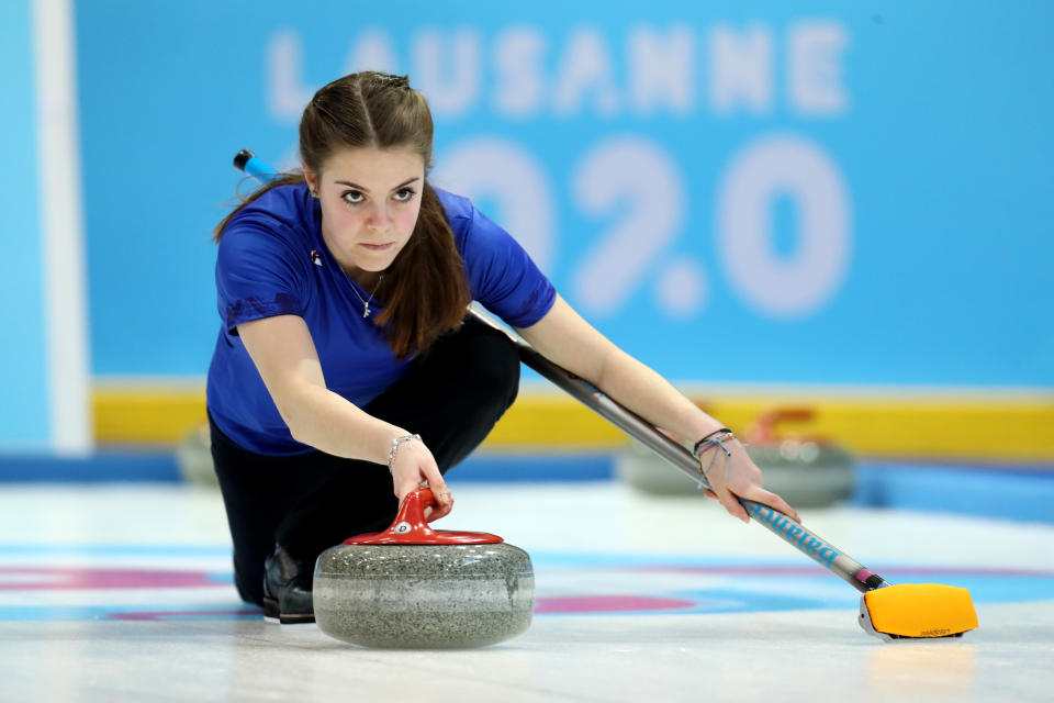 Una jugadora italiana de curling lanzando una piedra.