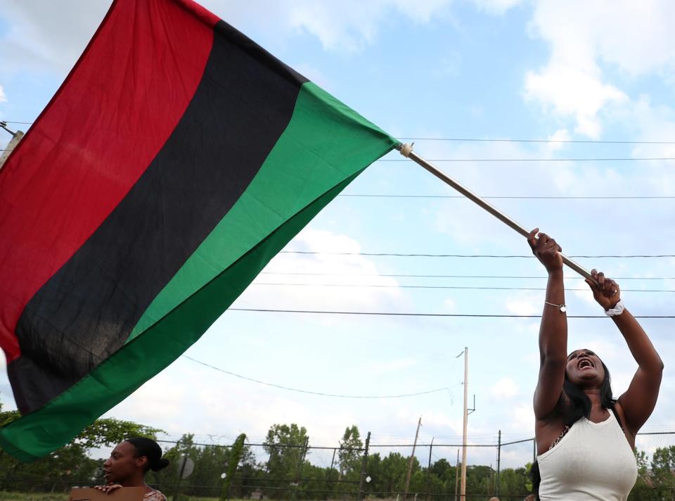 Danielle Taylor waves a Pan African flag during a protest Tuesday outside the Summit County Jail in Akron.