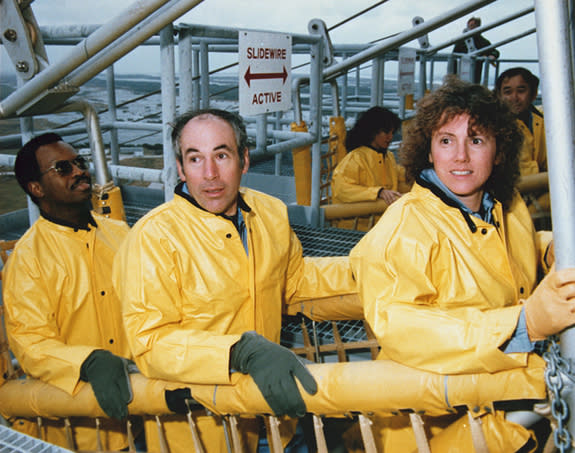 The STS-51L Challenger flight crew receives emergency egress training in the slide wire baskets. They are (L to R) Mission Specialist, Ronald McNair, Payload Specialist, Gregory Jarvis, Teacher in Space Partic