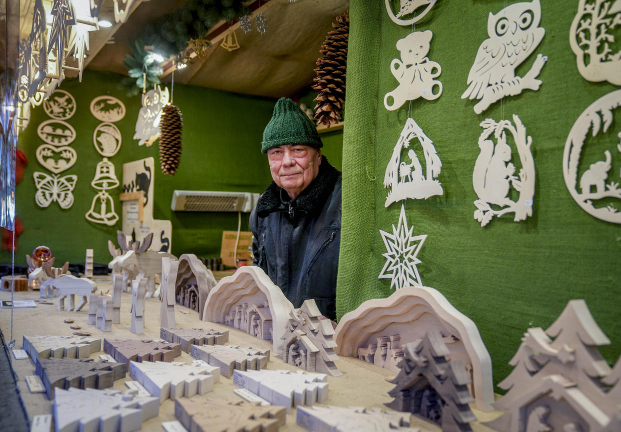 CORRECTS NAME OF PERSON IN THE PHOTO - Vendor Jens Knauer stands in his booth at the Christmas market in central Frankfurt, Germany, Tuesday, Nov. 23, 2021. Despite the pandemic inconveniences, stall owners selling ornaments, roasted chestnuts and other holiday-themed items in Frankfurt and other European cities are relieved to be open at all for their first Christmas market in two years, especially with new restrictions taking effect in Germany, Austria and other countries as COVID-19 infections hit record highs. (AP Photo/Michael Probst)