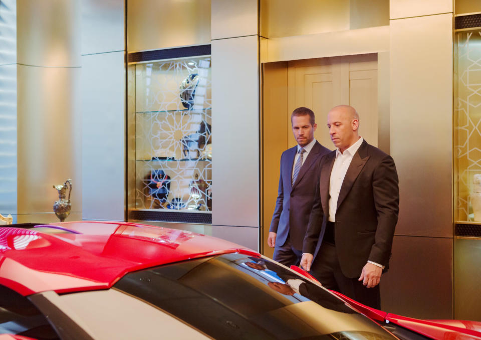 Paul Walker and Vin Diesel look at a car