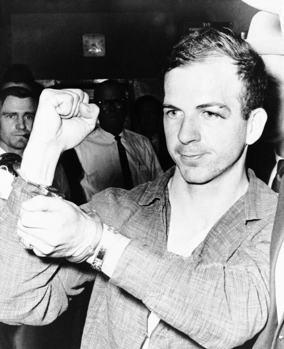 <p>Lee Harvey Oswald holds up his manacled hands as he is led thru the police station in Dallas on Nov. 22, 1963, where he was being held as a suspect in the assassination of President John Kennedy. He was charged with murder in the killing of a Dallas policeman who sought to arrest him in a theater several miles from the assassination scene. (Photo: AP) </p>