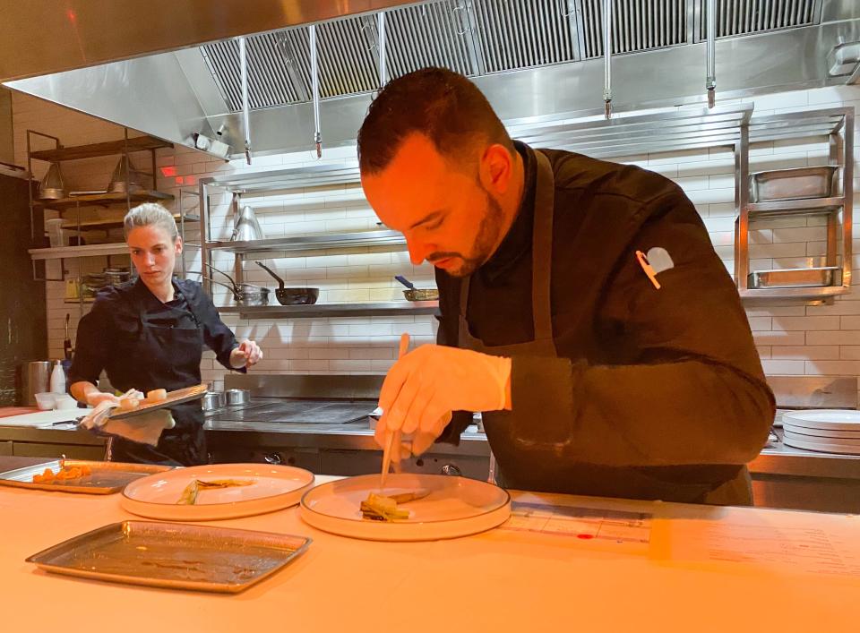 Antoine Boullay preparing a dish before it's sent out to the table, Alice is behind him