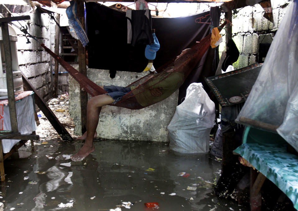 A man sleeps in a hmmock inside his house as flood waters continue to rise due to rains and high tide Thursday, Aug. 2, 2012 in Navotas City, north of Manila, Philippines. Exiting Typhoon Saola left nearly two dozens of people dead and forced 180,000 to flee their homes in the country. (AP Photo/Pat Roque)