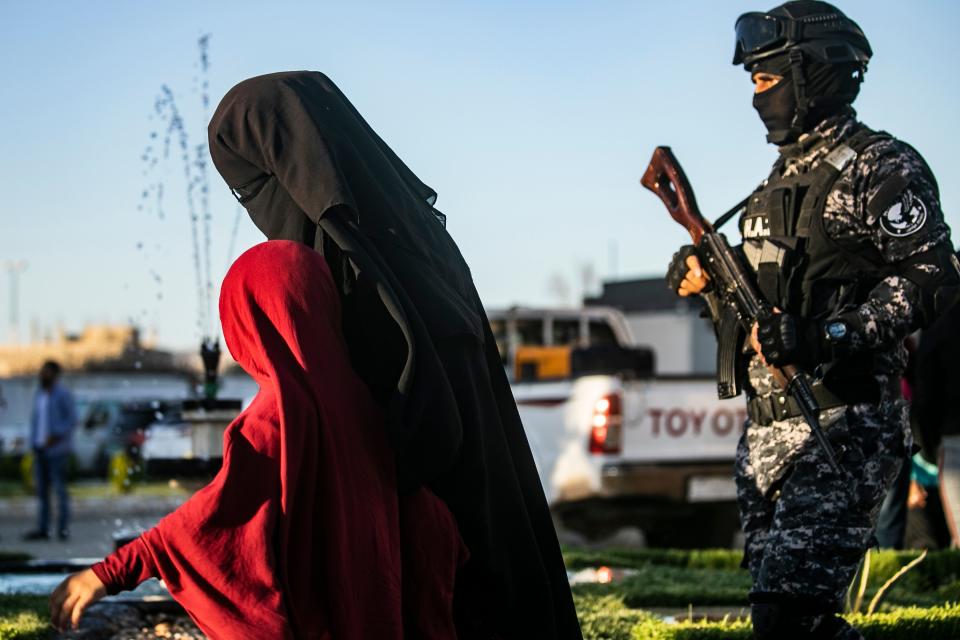 US-backed Syrian Democratic Forces (SDF) escort a fully veiled woman and a child in the northern Kuridish-Syrian city of Qamishli as Uzbek women and children linked to the Islamic State group are handed over to diplomats from the Central Asian country for repatriation, on May 29, 2019. - In total more than 300 Uzbeks were due to be sent home, spokesman Kamal Akef told AFP, as the Kurds look to transfer away thousands of foreign jihadists trapped in camps following the defeat of the IS "caliphate" by US-backed forces. Hundreds of Uzbeks are believed to have joined militants fighting in Iraq and Syria including IS. (Photo by Delil souleiman / AFP)        (Photo credit should read DELIL SOULEIMAN/AFP/Getty Images)