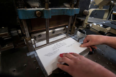 Lottie Small use the die stamping press at the workshop of Barnard and Westwood, who are printing the invitations for Britain's Prince Harry and Meghan Markle's wedding at Windsor Castle in May, London, Britain, March 22, 2018. Victoria Jones/Pool via Reuters