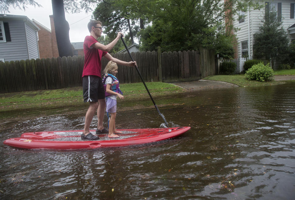 Eric Young stand-up paddleboards through flooded streets in Larchmont with his daughter, Emily Ruth, 5, after Hurricane Dorian brought heavy wind and rain to Norfolk, Va., on Friday, Sept. 6, 2019. (Kaitlin McKeown/The Virginian-Pilot via AP)