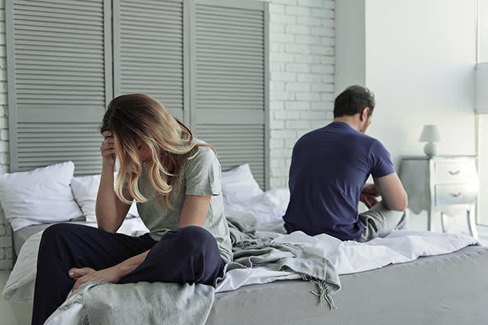 pareja triste sentada en la cama