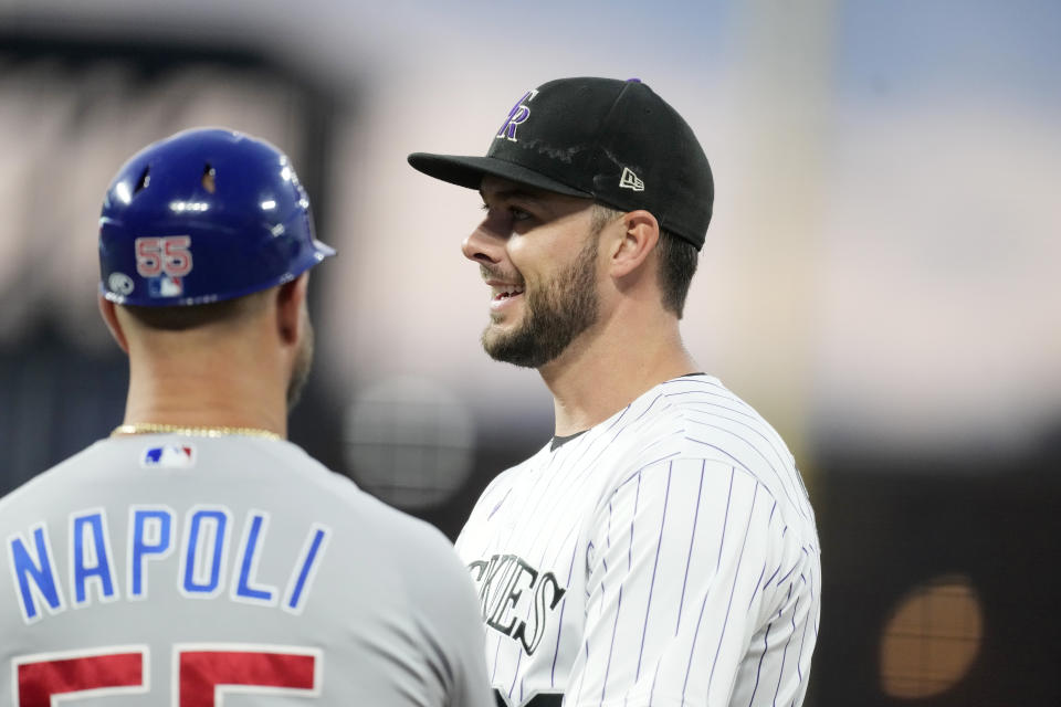 Colorado Rockies first baseman Kris Bryant, right, jokes with Chicago Cubs first base coach Mike Napoli during a break in the third inning of a baseball game after home plate umpire Brian O'Nora abruptly left the field Monday, Sept. 11, 2023, in Denver. (AP Photo/David Zalubowski)