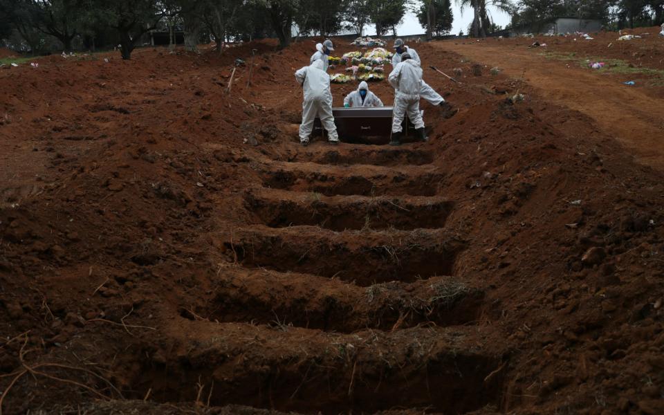 Gravediggers wearing protective suits bury a man who died from the coronavirus at Sao Luiz cemetery, in Sao Paulo, Brazil - Reuters