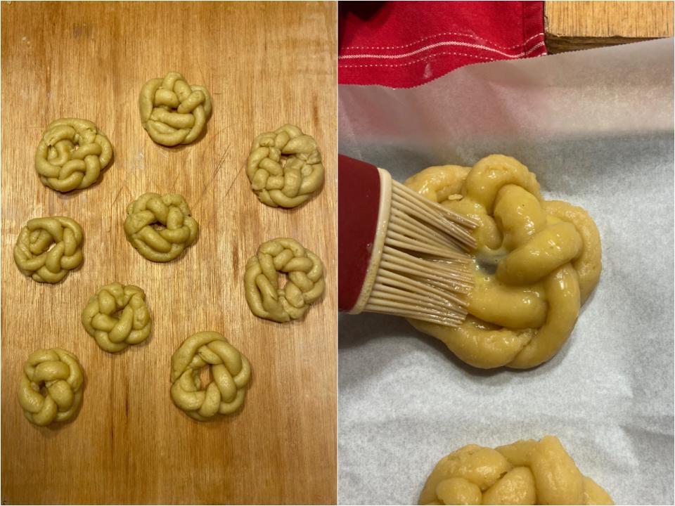 Nine uncooked braided dough wreaths of different sizes next to a wreath being covered in egg wash with a cooking brush.