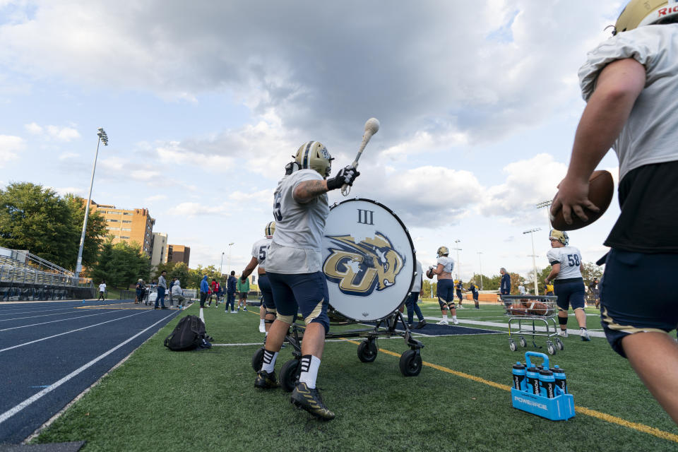 Gallaudet offensive lineman Agustin Bojorquez, center, beats a drum to signal a new period during football practice, Tuesday, Oct. 10, 2023, in Washington. Deaf and hard-of-hearing players feel the vibrations from the bass of the drum, which has replaced the use of a whistle since 1970. (AP Photo/Stephanie Scarbrough)