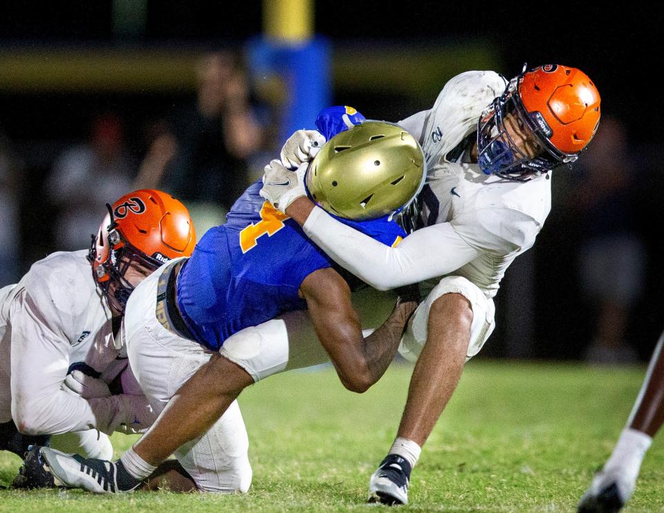 Benjamin linebacker Adam Balogoun-ali, right, and Patrick Downes, left, stop Cardinal Newman running back Jaylin Brown during their football game on October 20, 2023 in West Palm Beach, Florida.
