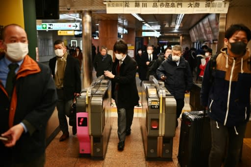 People wait for the train in Tokyo's Ginza area -- with fresh cases of new coronavirus emerging daily in Japan, the government has advised citizens to avoid mass gatherings, and cancelled public events