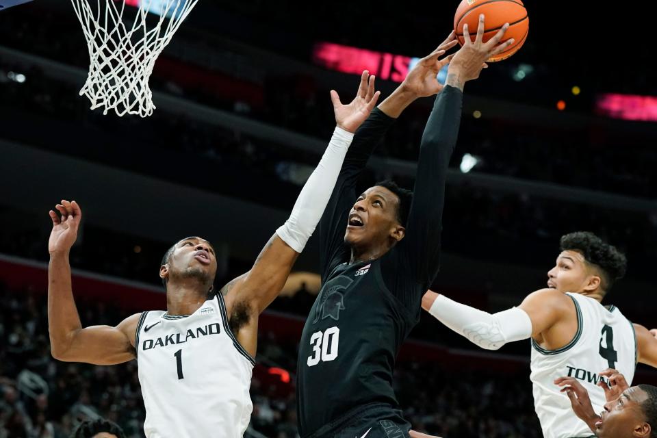 Michigan State forward Marcus Bingham Jr. (30) reaches for the rebound next to Oakland forward Jamal Cain (1) during the first half of an NCAA college basketball game, Tuesday, Dec. 21, 2021, in Detroit.