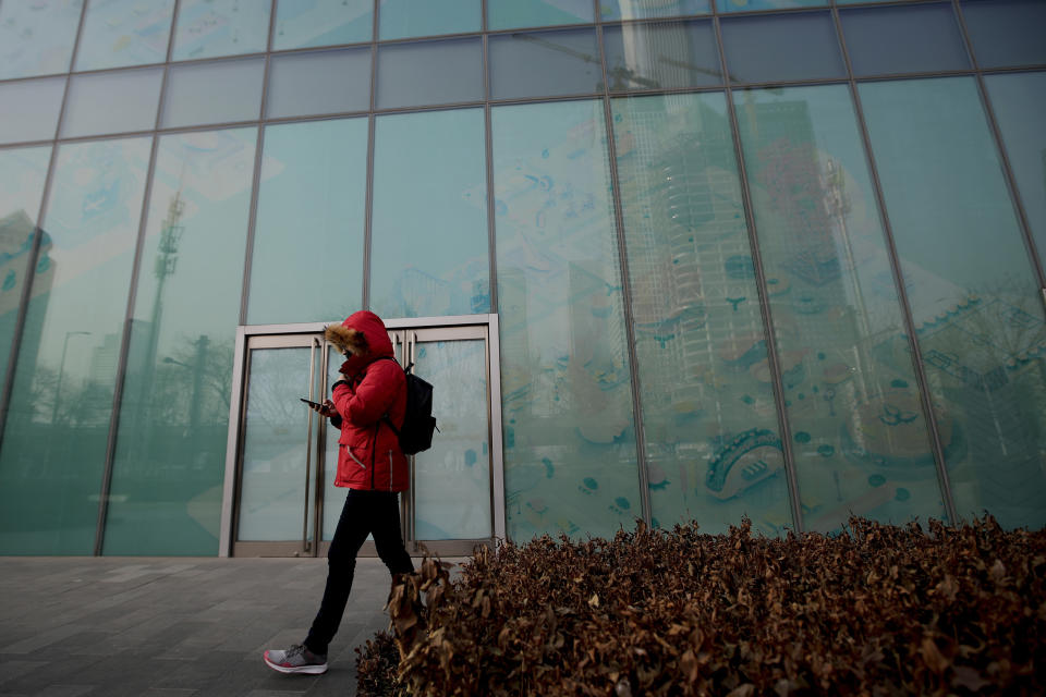 In this Jan. 12, 2019, photo, a man walks by a vacant retail space window panels at the Central Business District in Beijing. China's slowing economy is squeezing the urban workers and entrepreneurs the ruling Communist Party is counting on to help transform this country from a low-wage factory floor into a prosperous consumer market. (AP Photo/Andy Wong)