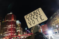 FILE - In this Nov. 4, 2020, file photo, Betsy Camardo, who supports Joe Biden, holds a sign outside the central counting board where ballots in the general election are counted in the city at the TCF Center in Detroit. President Donald Trump and his allies have fomented the idea of a “rigged election” for months, promoting falsehoods through various media and even lawsuits about fraudulent votes and dead voters casting ballots. While the details of these spurious allegations may fade over time, the scar it leaves on American democracy could take years to heal. (AP Photo/David Goldman, File)