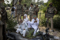Indian policemen stand guard as elderly Indian farmers sit in the shade during a protest in Noida on the outskirts of New Delhi, India, Friday, Sept. 25, 2020. Hundreds of Indian farmers took to the streets on Friday protesting new laws that the government says will boost growth in the farming sector through private investments, but they fear these are likely to be exploited by private players for buying their crops cheaply. (AP Photo/Altaf Qadri)