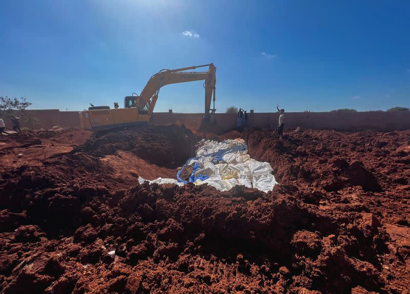Bodies of victims are placed at a mass grave after a powerful storm and heavy rainfall hit Libya