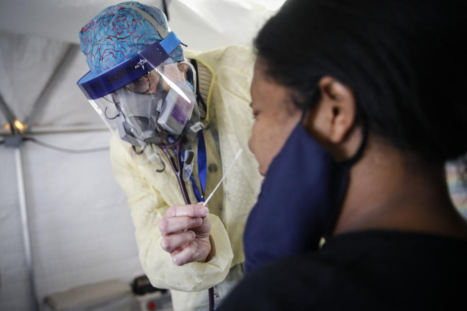 Catherine Hopkins, Director of Community Outreach and School Health at St. Joseph's Hospital, performs a COVID-19 swab on a patient in their testing tent, Monday, April 20, 2020, in Yonkers, N.Y. (AP Photo/John Minchillo)