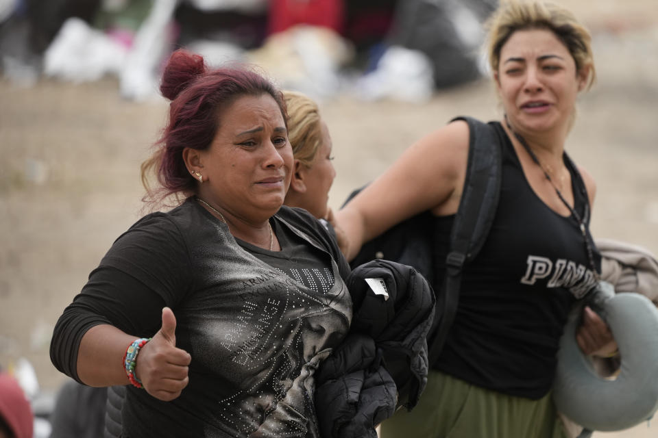 Women react as they are chosen by U.S. Border Patrol agents to be taken to processing after waiting for days between two border walls to apply for asylum, Friday, May 12, 2023, in San Diego. The border between the U.S. and Mexico was relatively calm Friday, offering few signs of the chaos that had been feared following a rush by worried migrants to enter the U.S. before the end of pandemic-related immigration restrictions. (AP Photo/Gregory Bull)