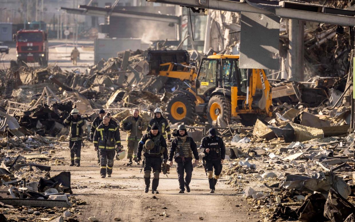 Ukrainian firefighters work next to a digger amid the rubble of the Retroville shopping mall - FADEL SENNA