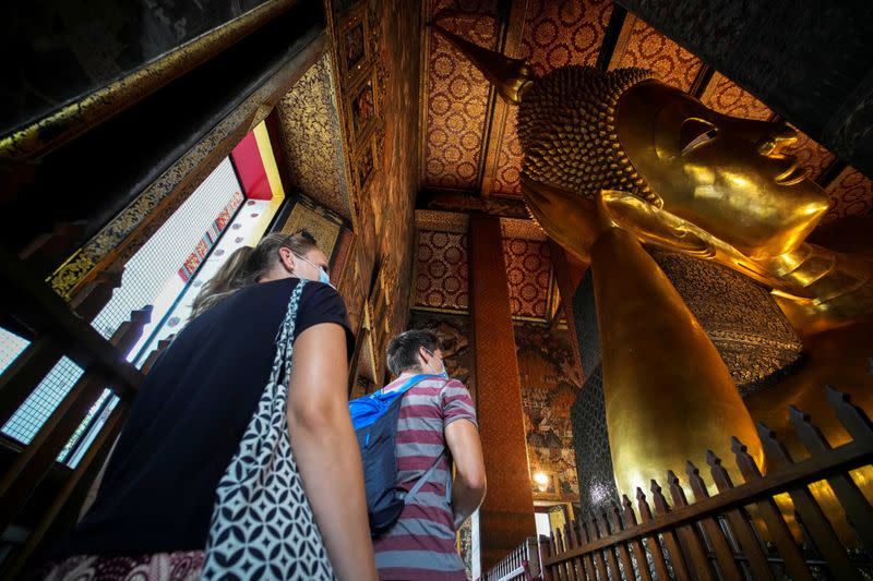FILE PHOTO: Foreign tourists are seen next to the Reclining Buddha at Wat Pho, a day after country's reopening campaign which is a part of the government's plan to jump start the pandemic-hit tourism sector in Bangkok