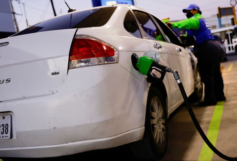 FILE PHOTO: A worker fills a car belonging to a Texas resident, with gasoline at a gas station following increased fuel prices in U.S., in Ciudad Juarez