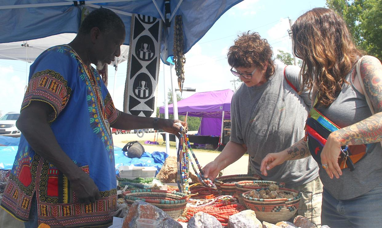 Julie Harries, (center), and Mary Kate Oreovicz look at necklaces being merchandised by Bagai Saho, the proprietor of African Imports at the 59th Annual Lawrence County Gem Mineral Fossil Show at the Lawrence County Fairgrounds on Friday, June 21, 2024.