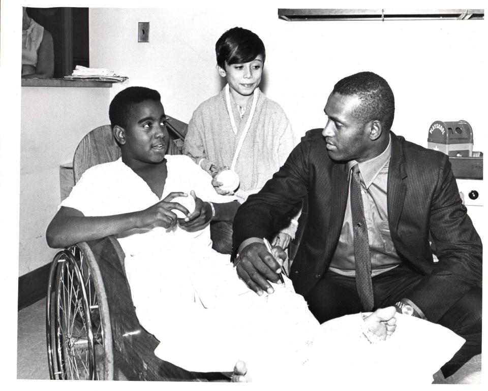Roberto Clemente paying a visit to Children's Hospital in Pittsburgh, signing the leg cast of Ernest Williams, left. Looking on is Louis Pennachio, who holds an autographed baseball. Clemente did this before "Robert Clemente Night" at Three Rivers Stadium on July 24, 1970. All proceeds from that game were donated to Children's Hospital to help parents who were unable to pay their medical bills.