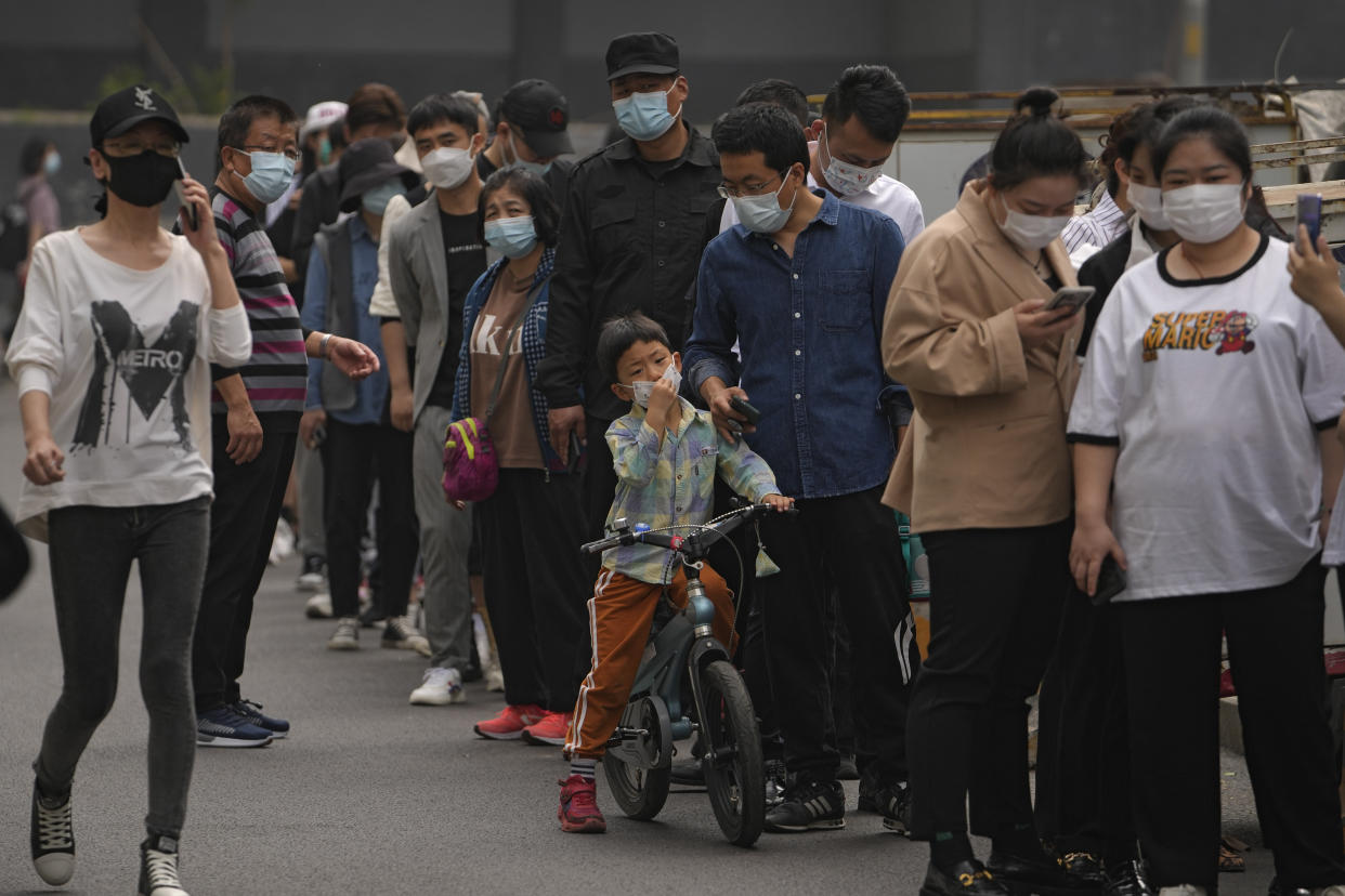 Residents and office workers wearing face masks line up for mass coronavirus testing outside a commercial office complex in Chaoyang district, Monday, April 25, 2022, in Beijing. Mass testing started Monday in the district, home to more than 3 million people in the Chinese capital, following a fresh COVID-19 outbreak. (AP Photo/Andy Wong)