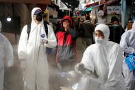 A man reacts as employees from a disinfection service company sanitize a traditional market in Seoul