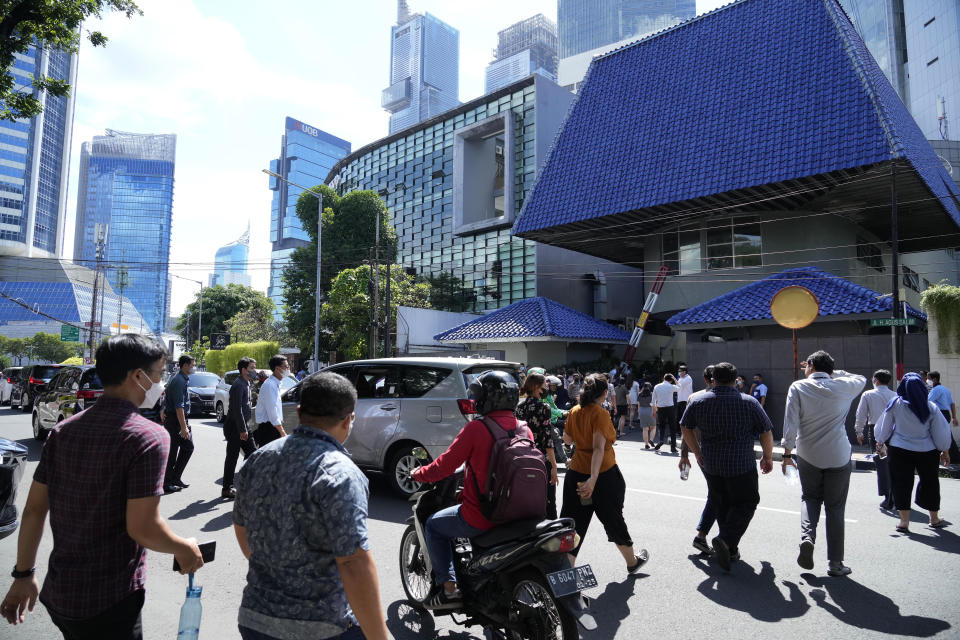 People walk out of an office building after being evacuated following an earthquake, Monday, Nov. 21, 2022, at the main business district in Jakarta, Indonesia. An earthquake shook Indonesia's main island of Java on Monday damaging dozens of buildings and sending residents into the capital's streets for safety. (AP Photo/Tatan Syuflana)