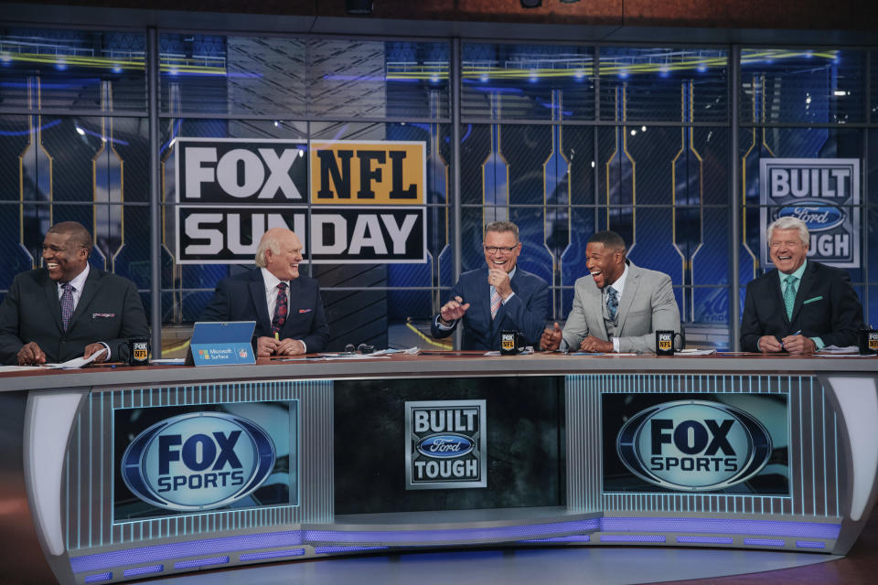 In this 2018 photo provided by Fox Sports, Curt Menefee, Terry Bradshaw, Howie Long, Michael Strahan and Jimmy Johnson, from left, get ready for the “Fox NFL Sunday” pregame show during the 2018 season at the Fox Sports studio in Los Angeles. The show, which started in 1994, was inducted into the NAB Broadcasting Hall of Fame earlier this year. (Fox Sports via AP)