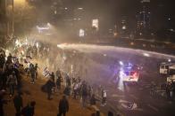 Israeli police use a water cannon to disperse demonstrators blocking a highway during a protest against plans by Prime Minister Benjamin Netanyahu's government to overhaul the judicial system in Tel Aviv, Israel, Monday, March 27, 2023. Tens of thousands of Israelis have poured into the streets across the country in a spontaneous outburst of anger after Prime Minister Benjamin Netanyahu abruptly fired his defense minister for challenging the Israeli leader's judicial overhaul plan. (AP Photo/Oren Ziv)