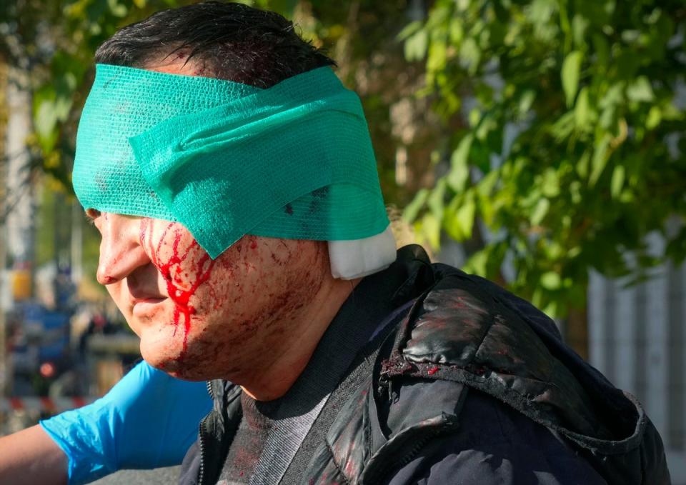 An injured man receives medical treatment at the scene of Russian shelling in Kyiv (AP)