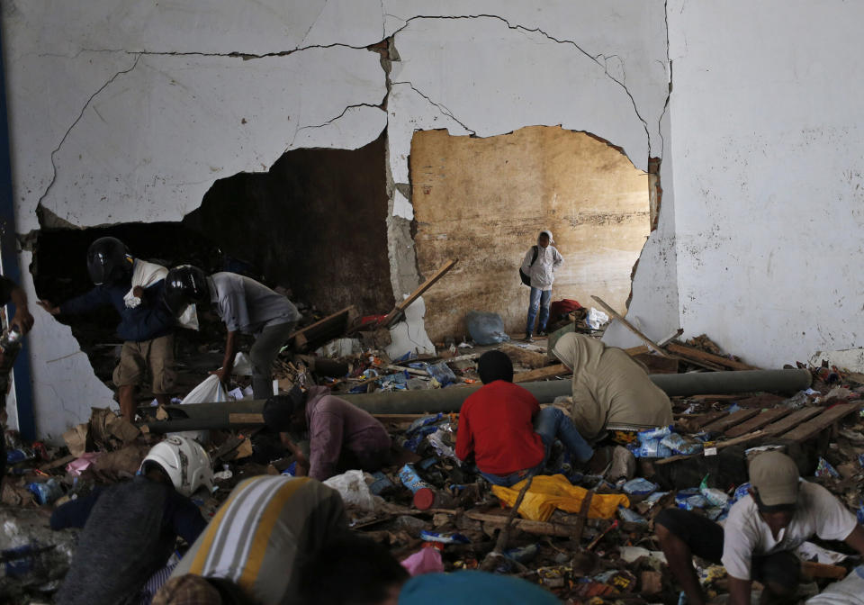 People scavenge for food inside an abandoned warehouse in an earthquake and tsunami-affected area in Palu, Central Sulawesi, Indonesia Indonesia, Wednesday, Oct. 3, 2018. Clambering over the reeking pile of sodden food or staking out a patch of territory, people who had come from devastated neighborhoods and elsewhere in the remote Indonesian city pulled out small cartons of milk, soft drinks, rice, candy and painkillers from the pile as they scavenge for anything edible in the warehouse that tsunami waves had pounded. (AP Photo/Dita Alangkara)