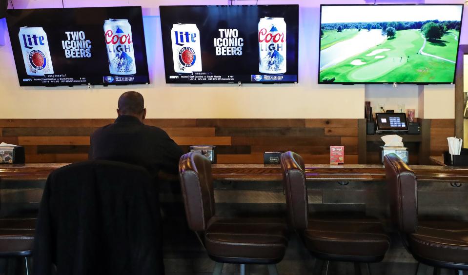 A patron has a drink at the bar at The Basement Bar and Grill in Akron.